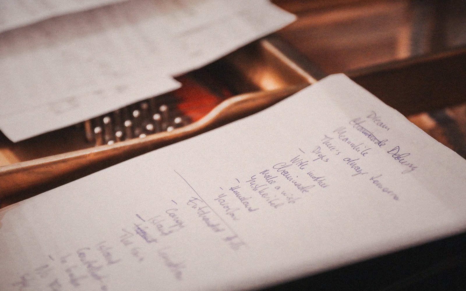 Handwritten song list resting on an open piano above the keys