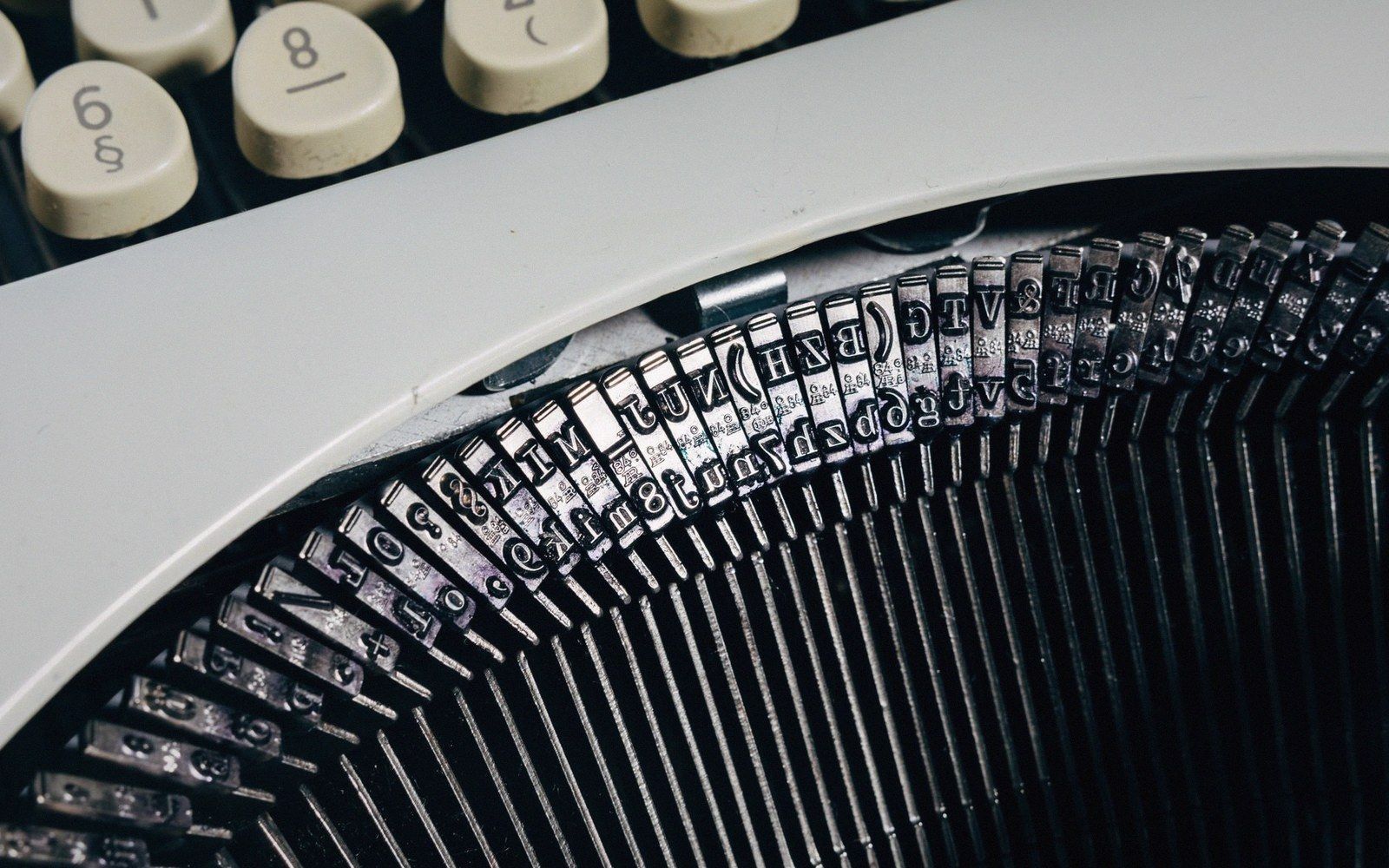 Close-up of a typewriter's metal type bars fanned out beneath the keyboard